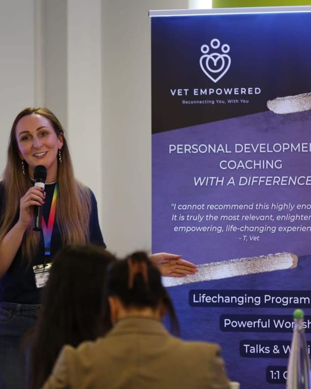 Katie Ford teaching with a microphone beside a Vet Empowered banner at a previous event.