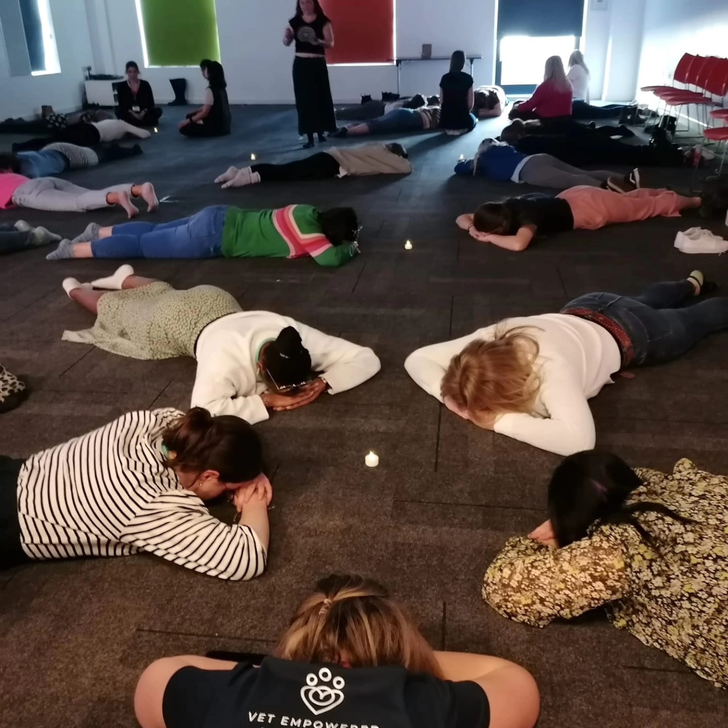 A room of veterinary professionals lying down by candlelight during a guided relaxation session.