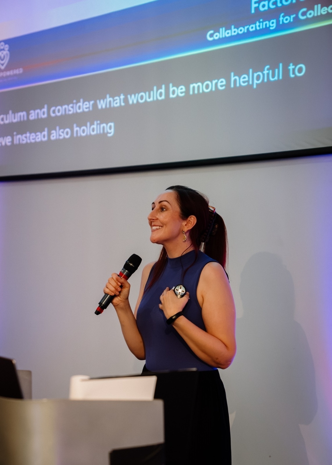 A Vet Empowered founder speaking with a microphone in front of a presentation screen.